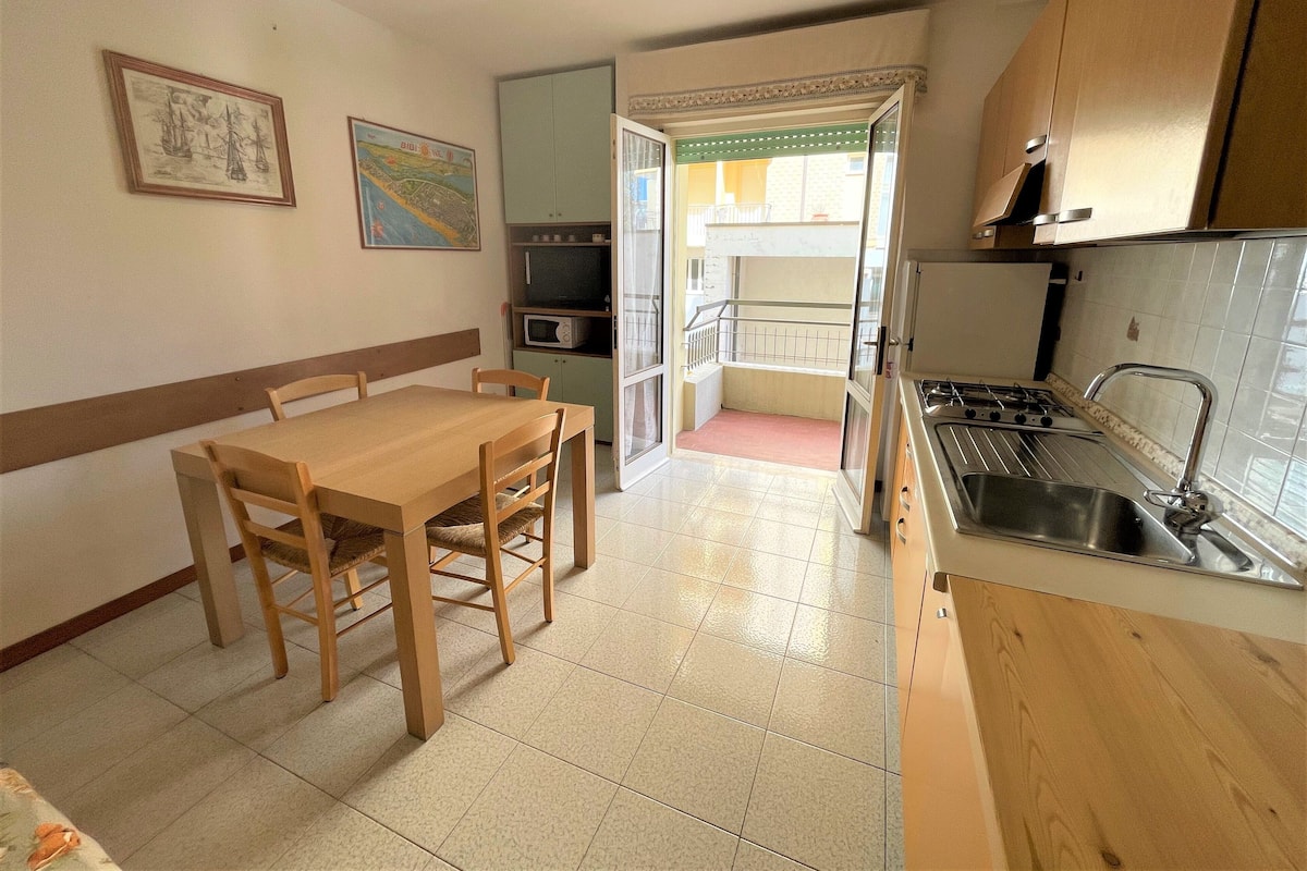 A compact kitchen with a dining table, chairs, a microwave, and a sink.