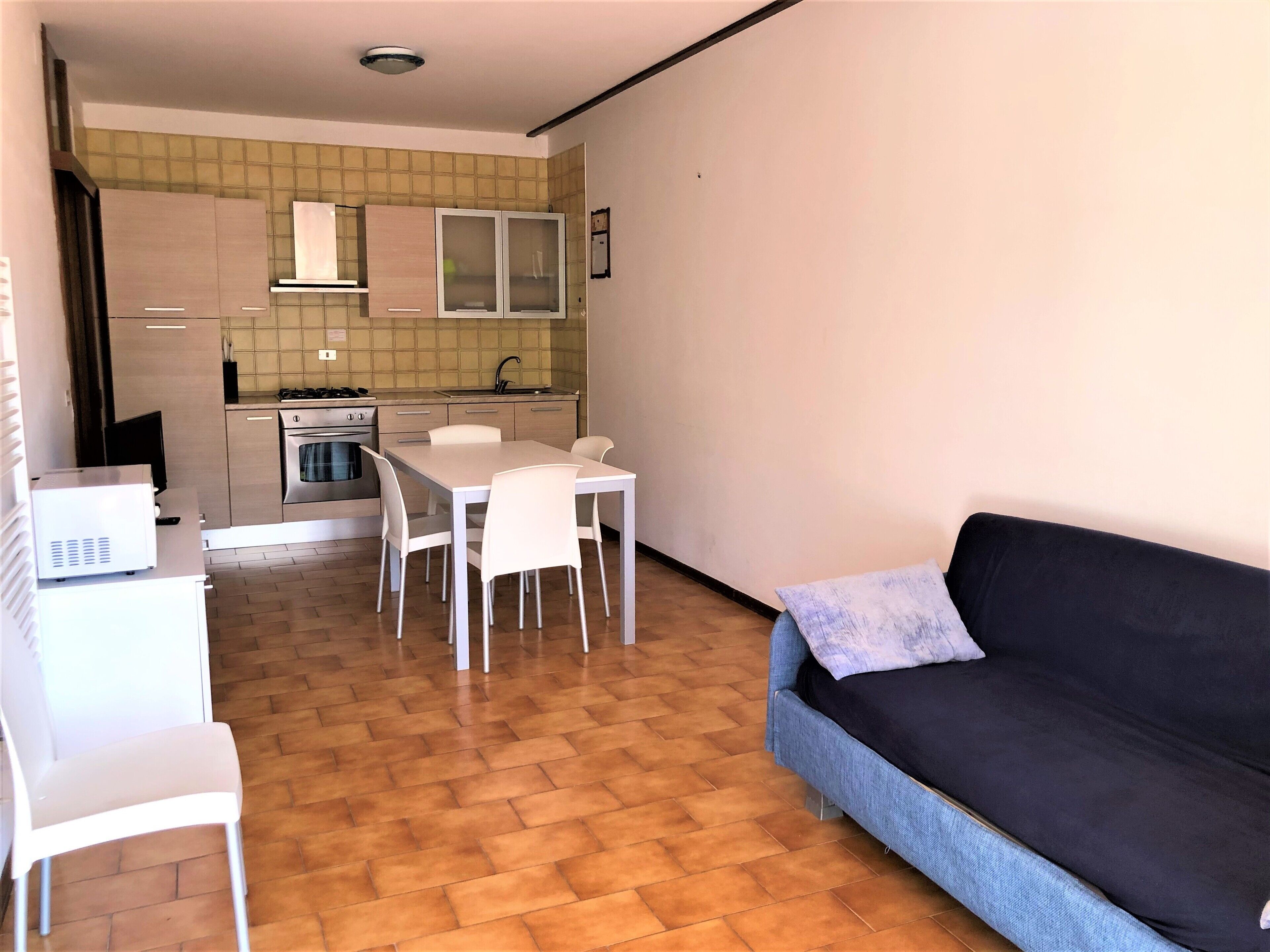 A compact living space with a kitchenette, a dining area with a table and chairs, and a sofa.