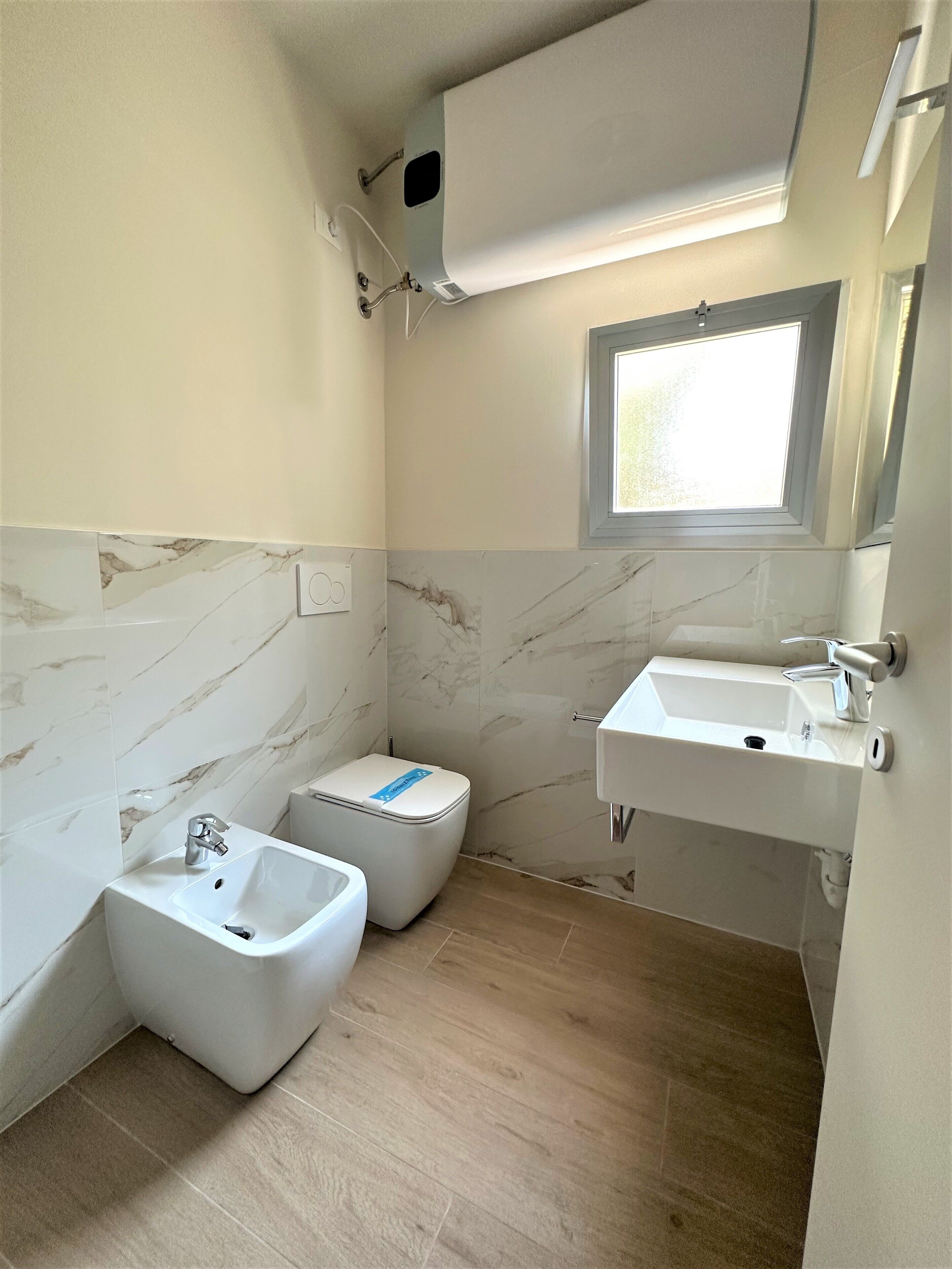 Un bagno con bidet, lavandino e finestra.