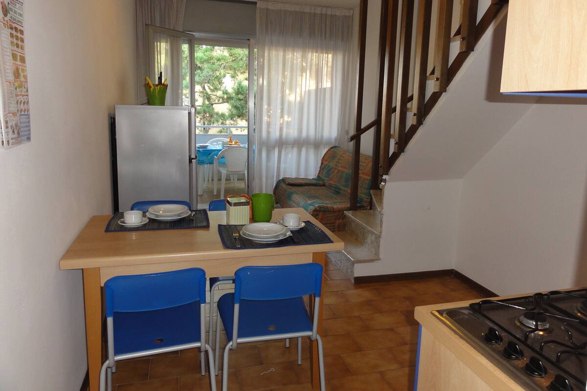 Eine kleine Küche mit Esstisch, Stühlen, Kühlschrank und Herd.