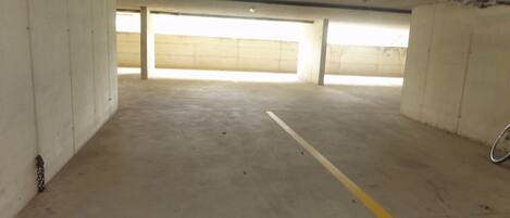 An empty parking garage with concrete walls and a yellow line on the floor.