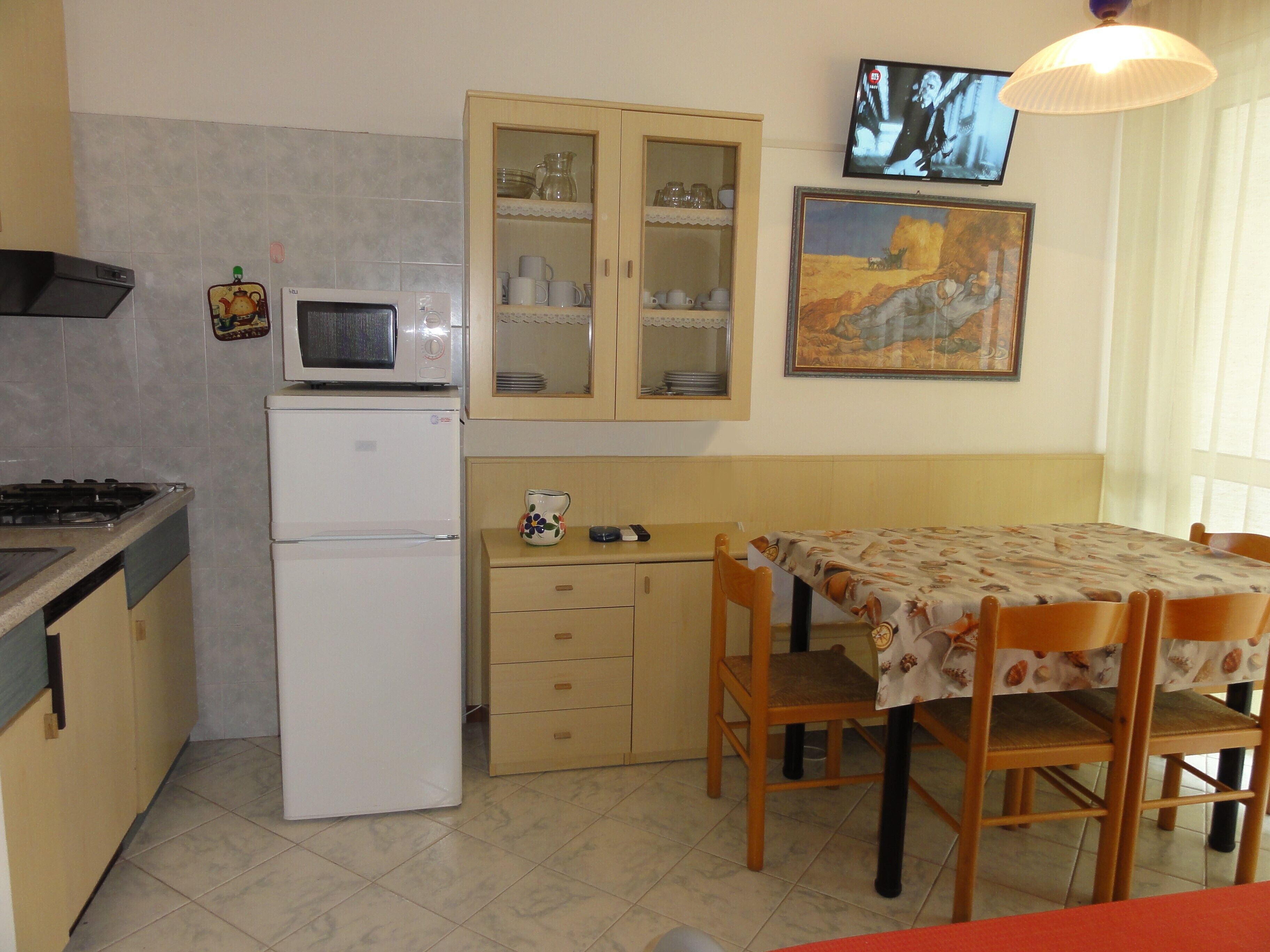 Une cuisine compacte équipée d’un four à micro-ondes, d’un réfrigérateur et d’un coin repas avec une table et des chaises.