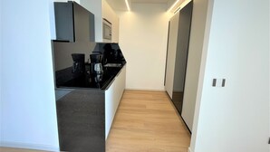 A modern kitchen with a black countertop, white cabinets, and a wooden floor.