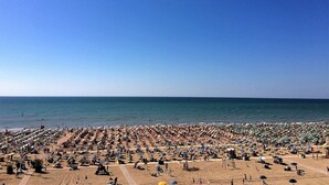 A crowded beach with numerous umbrellas and sun loungers.