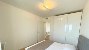 A modern bedroom with a bed, a wardrobe, and a door leading to a bathroom.