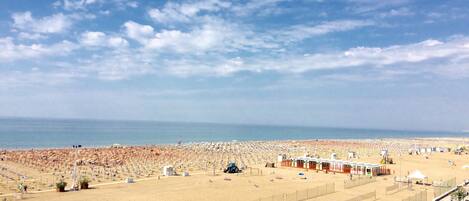 Ein Strand mit Volleyballfeld, Sonnenschirmen und Strandhäusern.