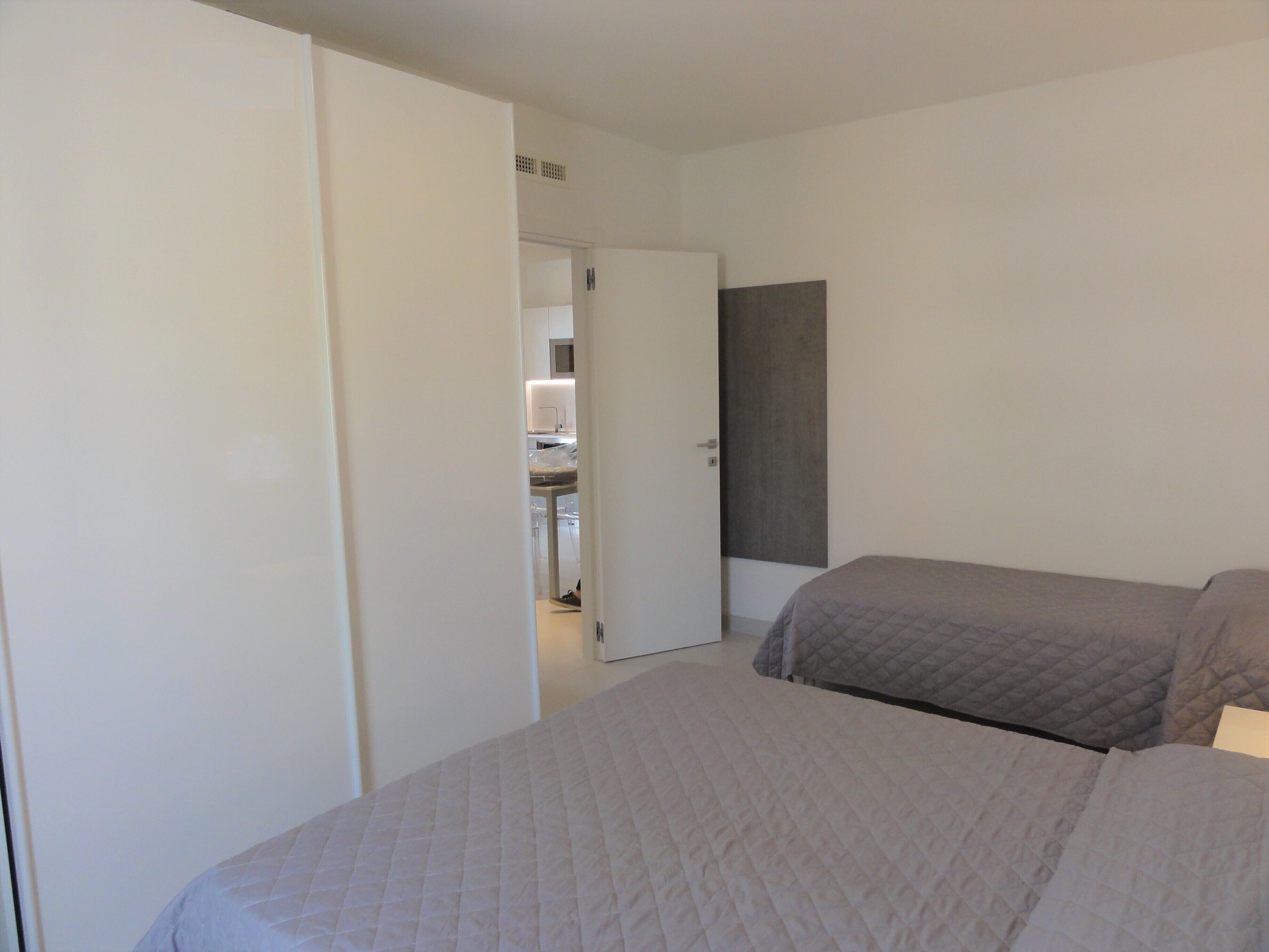 Un dormitorio con dos camas, un armario y una puerta que da al baño.