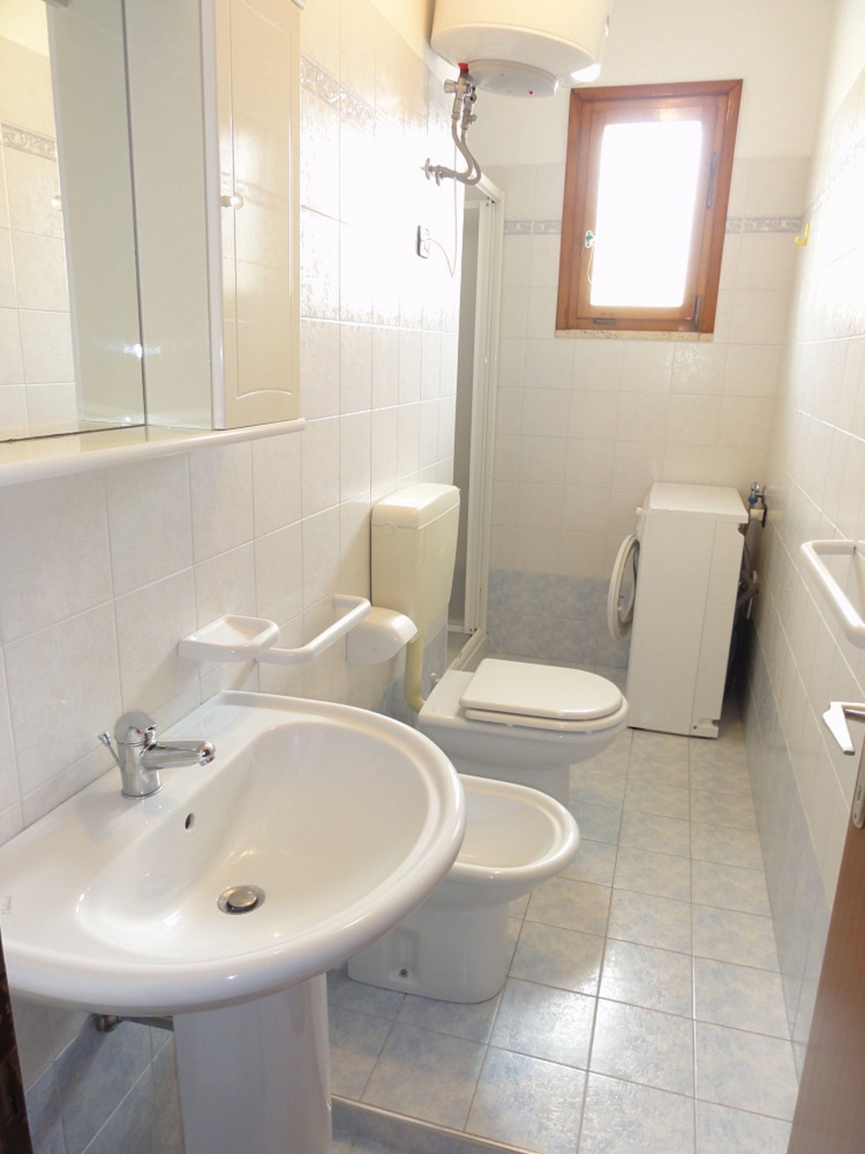 Une petite salle de bain comprenant un lavabo, deux toilettes et une douche.