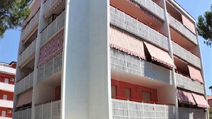 Un edificio de varios pisos con balcones, piscina y cielo despejado.