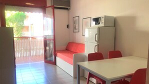 Un espacio habitable compacto con kitchenette, comedor y balcón.
