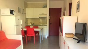 Un espacio habitable compacto con kitchenette, comedor y televisor sobre un mueble.