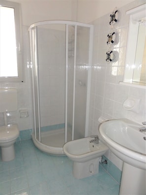 Un baño con cabina de ducha, inodoro, bidé y lavamanos.