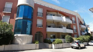 Um edifício de vários andares com uma estrutura cilíndrica central, varandas e céu claro.
