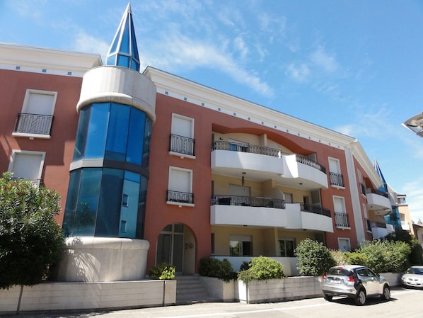 Un edificio de varios pisos con una estructura cilíndrica central, balcones y un cielo despejado.