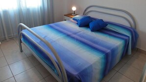 A bedroom with a bed, pillows, a nightstand, and a lamp. - Condominio Molent (San Michele al Tagliamento)