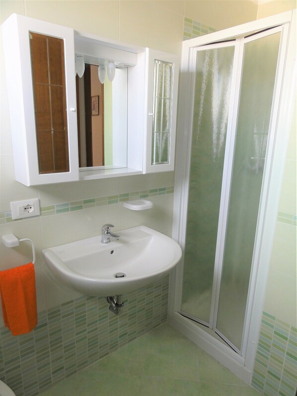 A bathroom with a white sink, a mirror, and a shower enclosure.