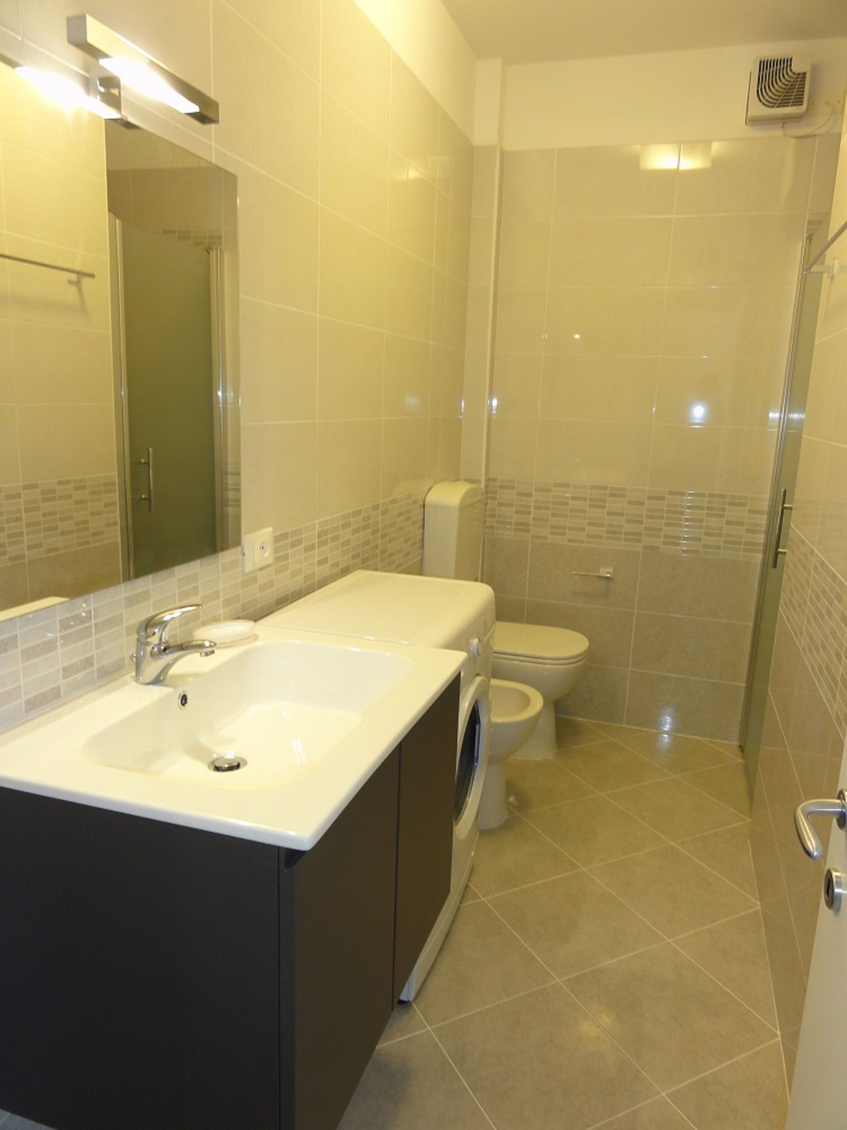 Een badkamer met een dubbele wastafel, toilet en douche.