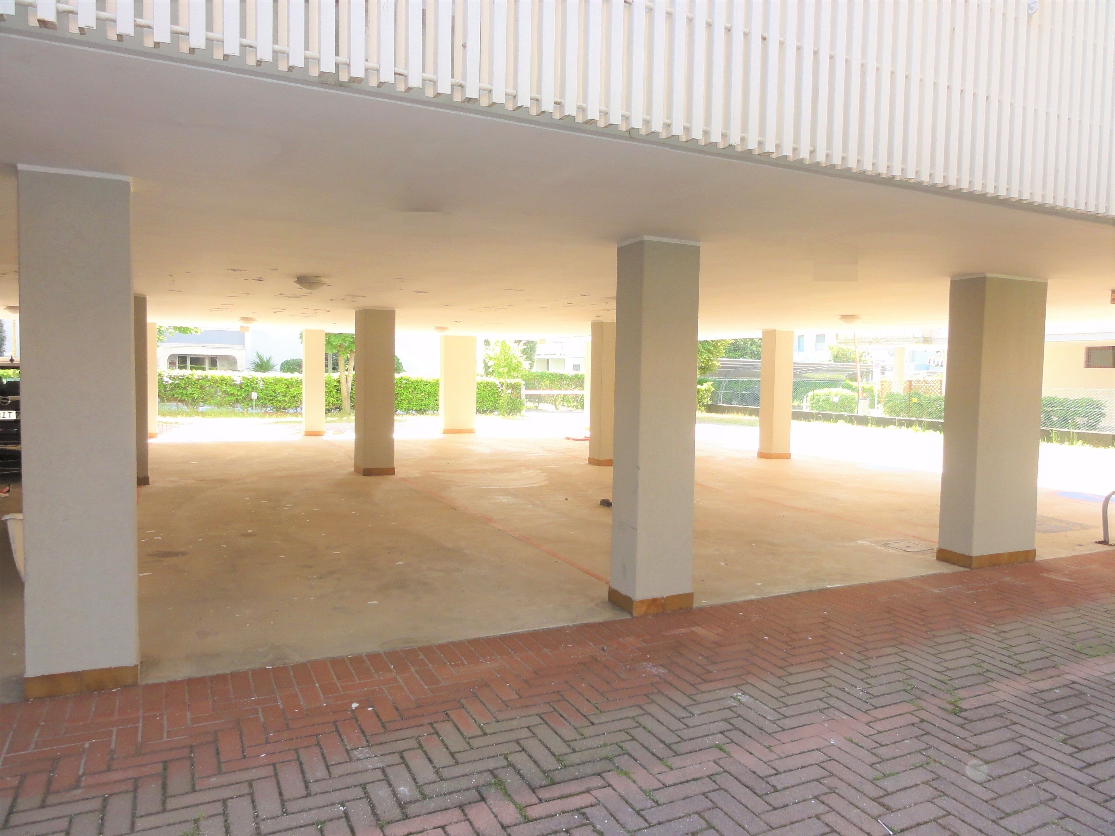 An indoor open space with a tiled floor, white pillars, and a brick border.