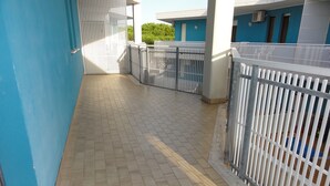 A corridor with tiled flooring, white metal railings, and a blue wall. - Condominio Simma 2 (San Michele al Tagliamento)