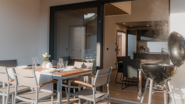 Un comedor moderno con un separador de vidrio, una mesa de madera y sillas.