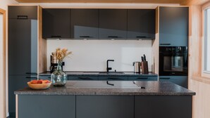 Una cocina moderna con armarios oscuros, una isla central y un horno empotrado.