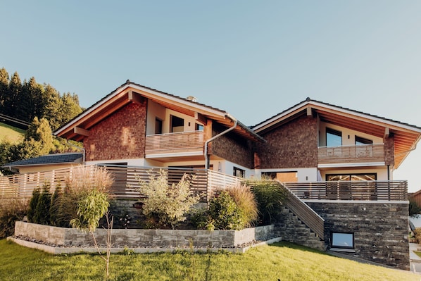 Een modern herenhuis met twee verdiepingen, een stenen gevel, een balkon en een stenen steunmuur.