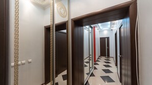 A hallway with a checkered floor, a mirror, and a door leading to another room. - Kiev Rent Apartments (Kyiv)