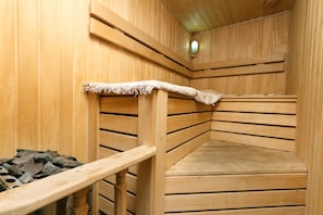 Una sauna con bancos de madera y un banco de piedra.