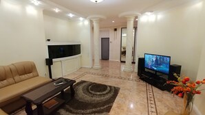 A living room with a beige sofa, a flat-screen TV, a coffee table, and a decorative rug. - Kiev Rent Apartments (Kyiv)