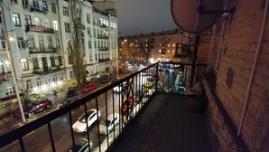 A nighttime view of a city street from a balcony with a metal railing, buildings, and parked cars. - Kiev Rent Apartments (Kyiv)