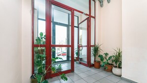 Ein Korridor mit großen Glastüren, Topfpflanzen und Fliesenboden.