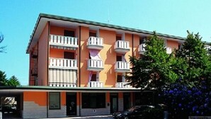 A multi-story hotel with balconies, a parking area, and a sign for "Italienline." - Condominio Storione (San Michele al Tagliamento)