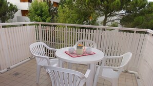 A white outdoor patio with a round table and four chairs, surrounded by a white fence. - Condominio Venere (San Michele al Tagliamento)