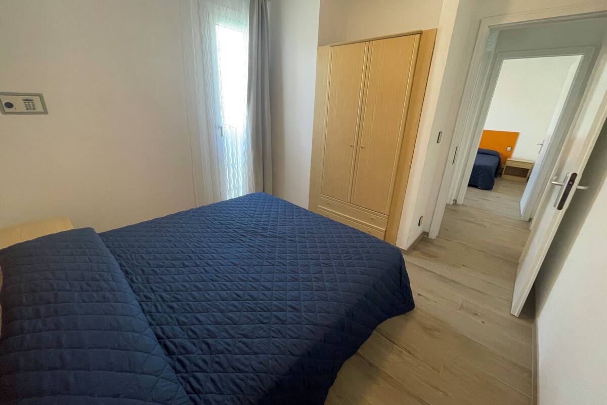 Une chambre à coucher avec un grand lit, une armoire et une porte donnant sur une autre pièce.