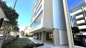 A modern building with multiple floors, large windows, and a parking area with cars. - Residence Eurostar (San Michele al Tagliamento)