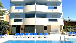 A multi-story hotel with a swimming pool, featuring a modern architectural design with balconies and a clear blue sky. - Residence Eurostar (San Michele al Tagliamento)