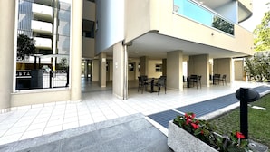 A modern building with a covered outdoor area, multiple balconies, and outdoor seating. - Residence Eurostar (San Michele al Tagliamento)