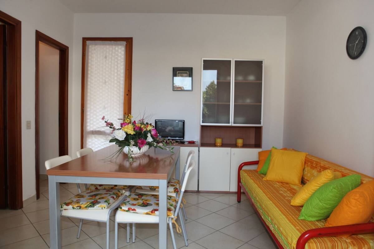 A compact living space with a dining area, a sofa, and a television.