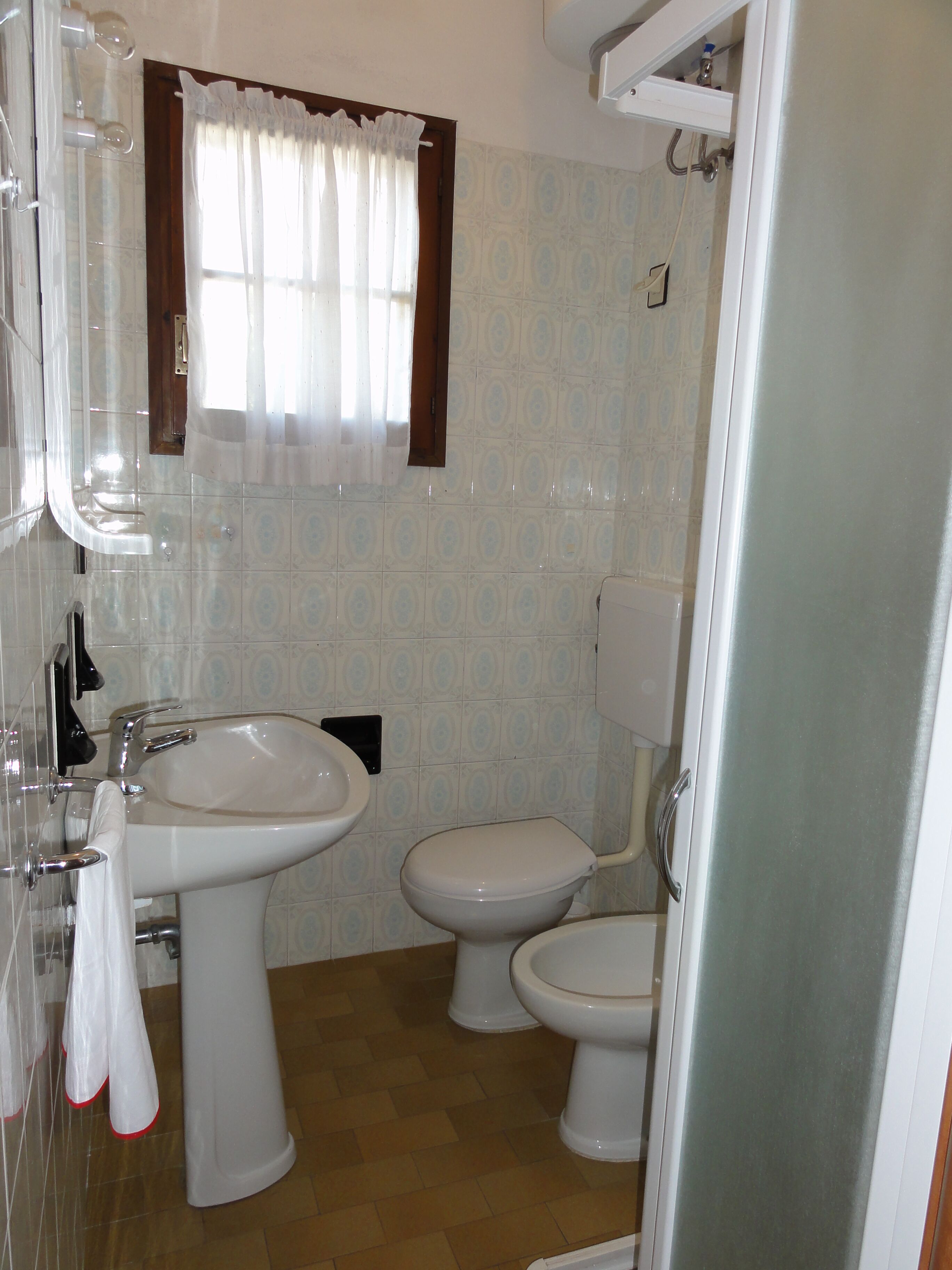 A bathroom with two toilets, a sink, and a shower.
