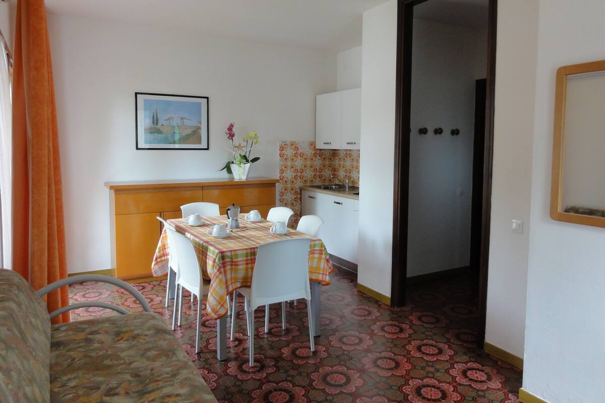 A compact living space with a dining area, kitchenette, and a door leading to another room.