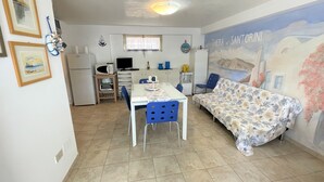 A small, well-lit room with a dining table, chairs, a sofa, and a kitchen area. - Villa Auriga (San Michele al Tagliamento)