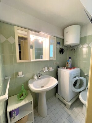 Une petite salle de bain comprenant un lavabo, un miroir et un lave-linge.