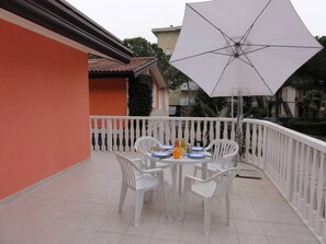 Enjoy a meal for two on the balcony with a shaded table and comfortable seating.
