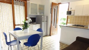 A compact kitchen with a dining area, a sofa, and a TV. - Villa Galasso (San Michele al Tagliamento)