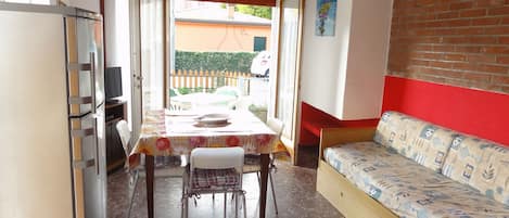 A compact living space with a dining area, a sofa, and a kitchen area.
