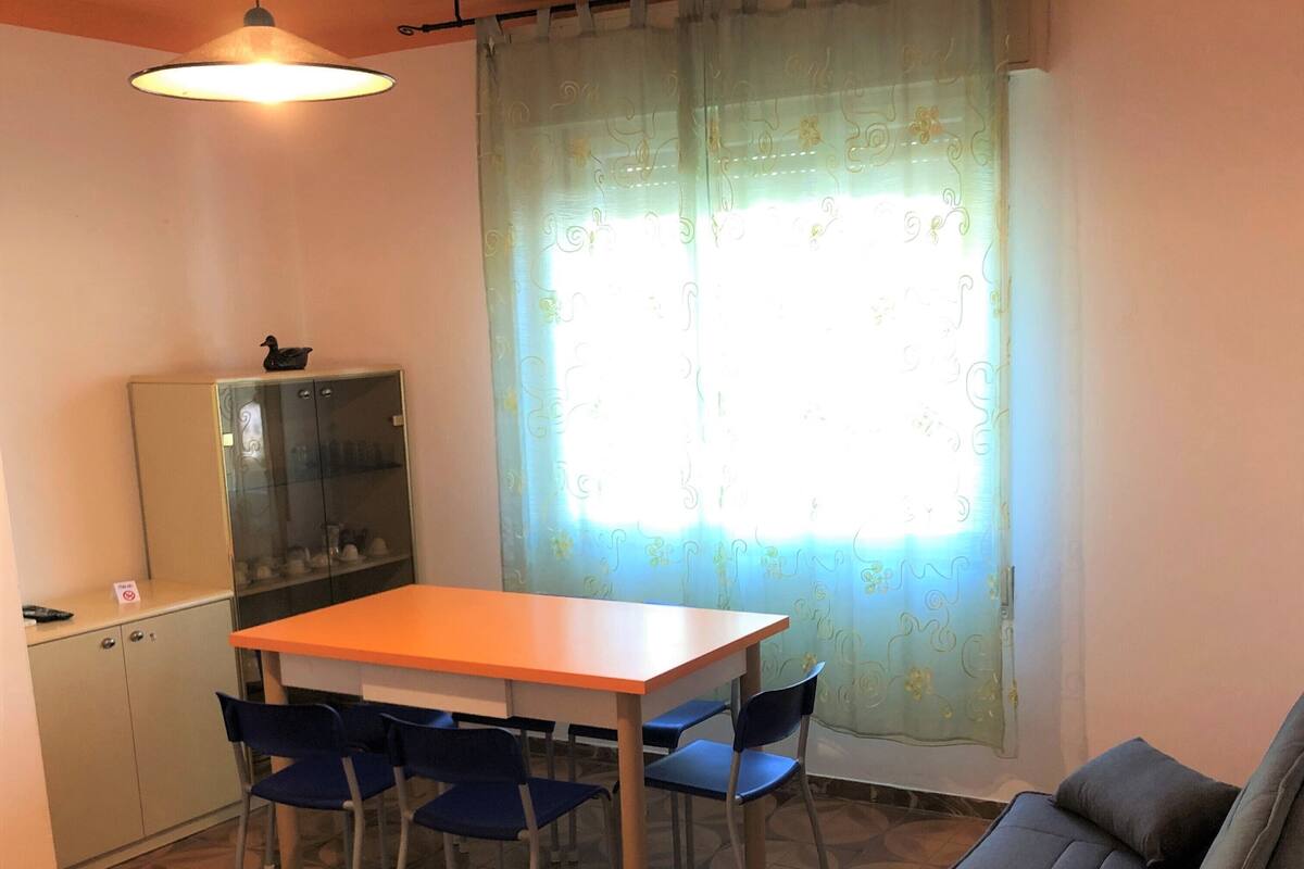 Un espacio habitable pequeño con una mesa de comedor, sillas azules, un sofá, un armario y un suelo estampado.