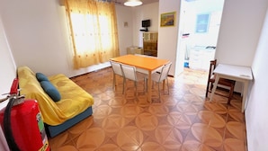 A compact living space with a sofa, a dining table, and a small kitchen area.