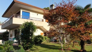 A two-story building with a balcony, a clear sky, and a tree with autumn leaves.