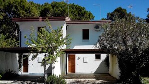 Un bâtiment à deux étages, doté d’une façade blanche, d’une porte en bois et d’une petite fenêtre.