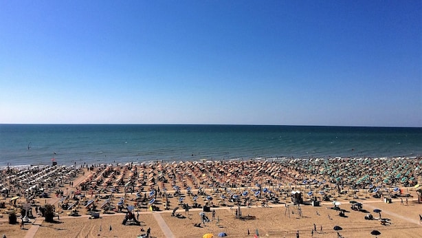Une plage bondée, avec de nombreux parasols et des chaises longues.